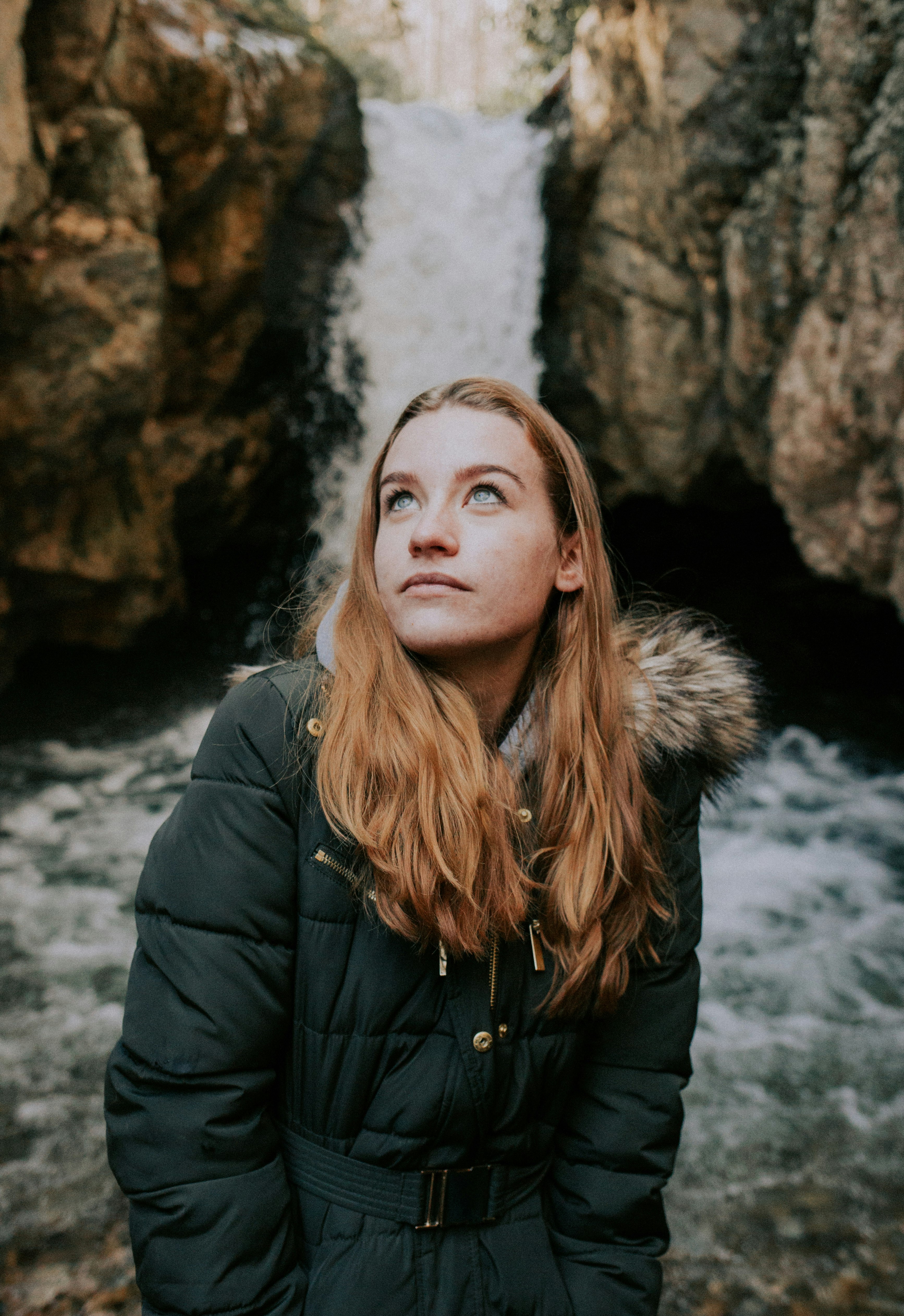 woman wearing black bobble jacket standing near waterfalls